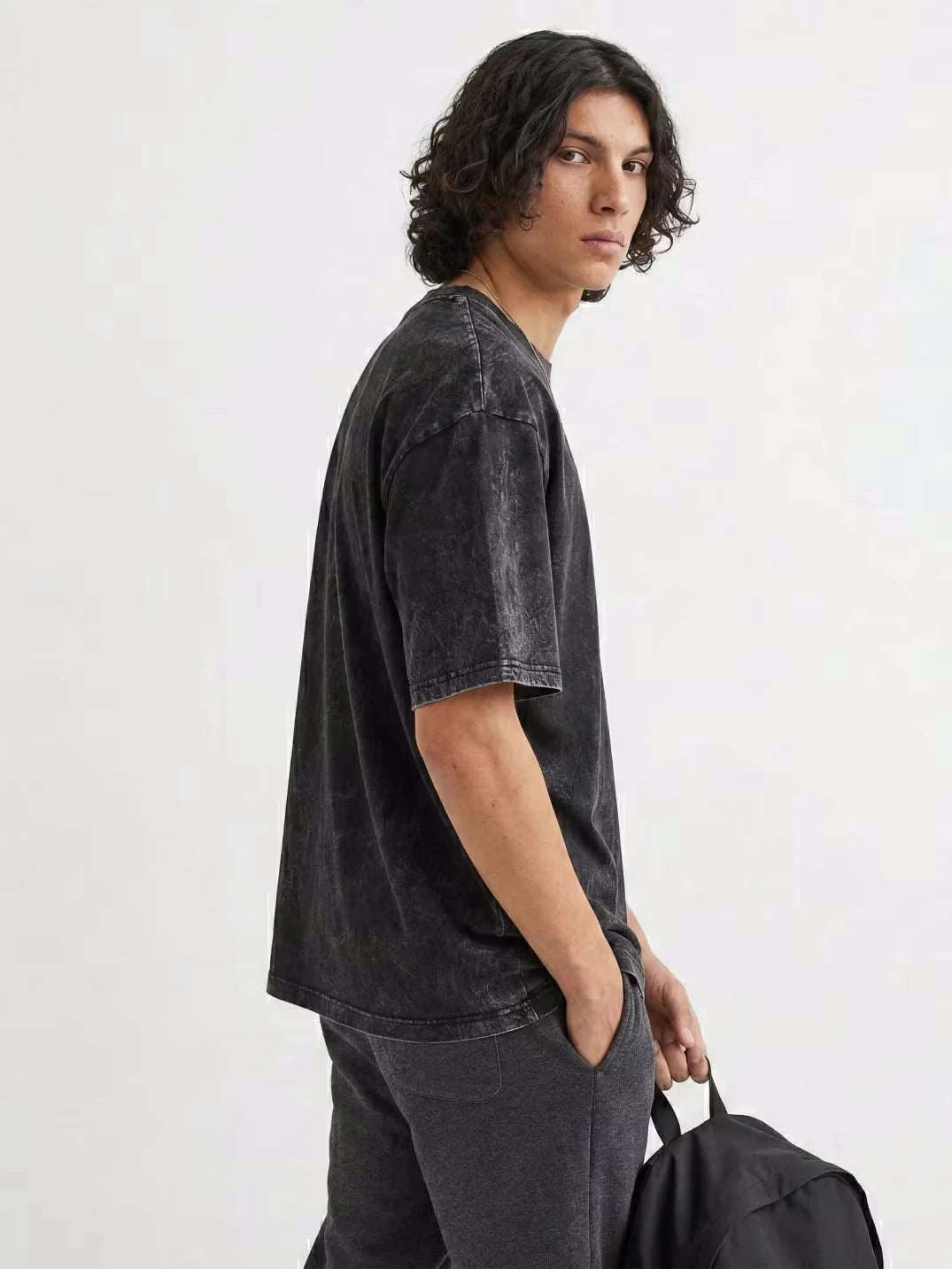 Male model wearing free Palestine T-shirt with Arabic calligraphy print and oversized drop shoulder fit on white background by Zaroodi