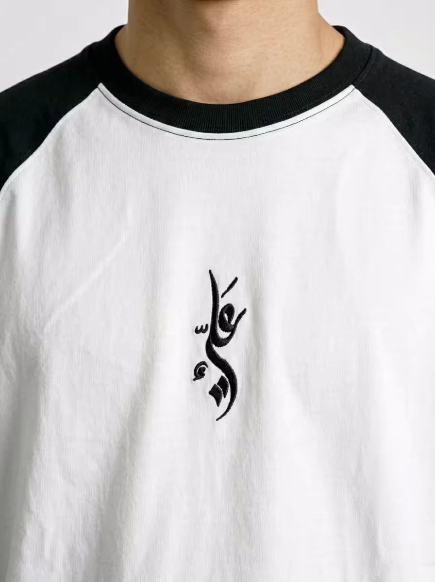 Close-up Arabic Ali embroidery on minimalist raglan t-shirt by Zaroodi